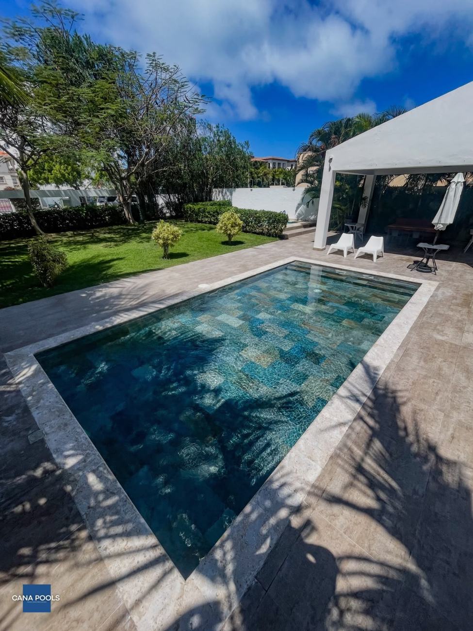 Piscina terminada por Cana Pools con revestimiento en piedra verde y terraza